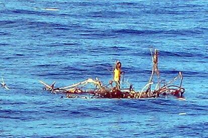 El náufrago Rizal Shahputra, de pie sobre las ramas de un árbol, hace señales al barco mercante que le salvó en el océano Índico.