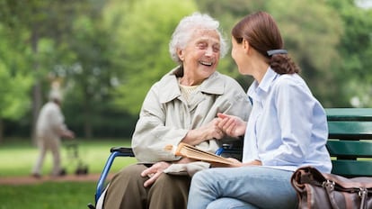 Dos mujeres charlan sentadas en un parque.