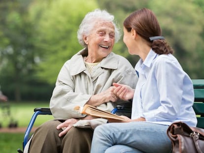 Dos mujeres charlan sentadas en un parque.