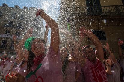 Los asistentes al Chupinazo se refrescan con cubos de agua lanzados desde los balcones de la plaza del Ayuntamiento de Pamplona.