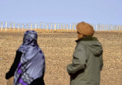 Dos personas contemplan la valla que separa las zonas controladas por Marruecos y el Frente Polisario en el S&aacute;hara Occidental.