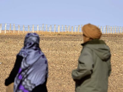 Duas pessoas contemplam a cerca que separa as zonas controladas pelo Marrocos e a Frente Polisário no Saara Ocidental.