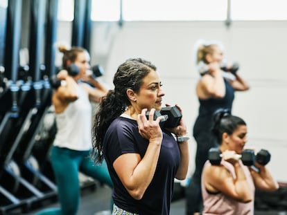 Woman doing dumbbell squats during fitness class in gym