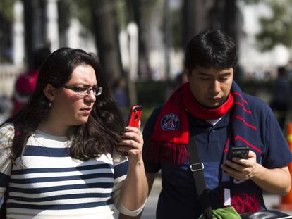 Dos mexicanos consultan su celular en la Ciudad de M&eacute;xico.