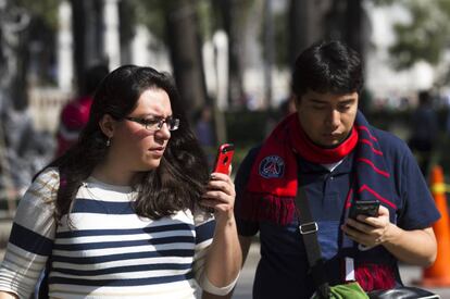 Dos mexicanos consultan su celular en la Ciudad de M&eacute;xico.