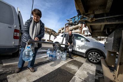 Dos vecinos de l'Estartit llenan varias garrafas de agua potable de una cuba para el uso diario.