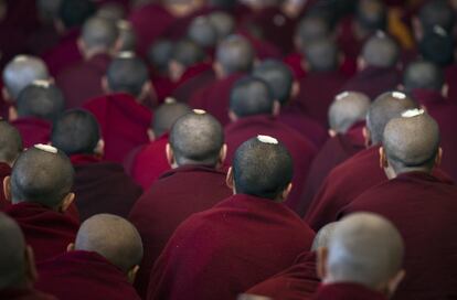 Varios monjes budistas tibetanos exiliados, con semillas ceremoniales en sus cabezas afeitadas, escuchan una charla religiosa de su líder espiritual —el Dalai Lama— en el templo de Tsuglakhang, en Dharmsala (India).