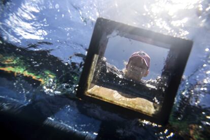 Belinda Morrow utiliza una caja con fondo de vidrio para mirar bajo el agua desde el bote, mientras se planta coral en un arrecife dentro de la zona protegida.
