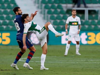 El delantero del Elche Lucas Boyé (derecha) pelea por el balón con el defensa del Huesca Dimitrios Siovas este sábado en el estadio Martínez Valero.