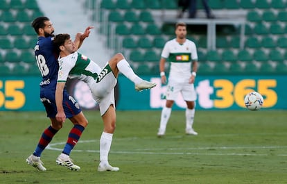 El delantero del Elche Lucas Boyé (derecha) pelea por el balón con el defensa del Huesca Dimitrios Siovas este sábado en el estadio Martínez Valero.