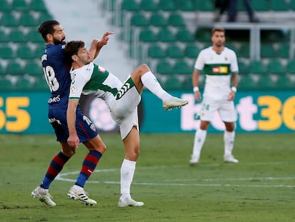 El delantero del Elche Lucas Boyé (derecha) pelea por el balón con el defensa del Huesca Dimitrios Siovas este sábado en el estadio Martínez Valero.