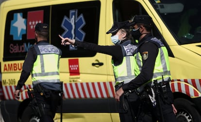 Tres agentes de policía, frente a una ambulancia.