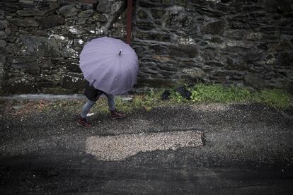 Una vecina pasa ante un tramo abierto en un camino de O Contrasto (O Porriño) donde se descubrió la existencia de lindano bajo el firme asfaltado.