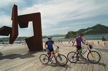 El 'bidegorri', o camino rojo para los ciclistas en San Sebastián, junto a la escultura de Oteiza 'Construcción vacía'.