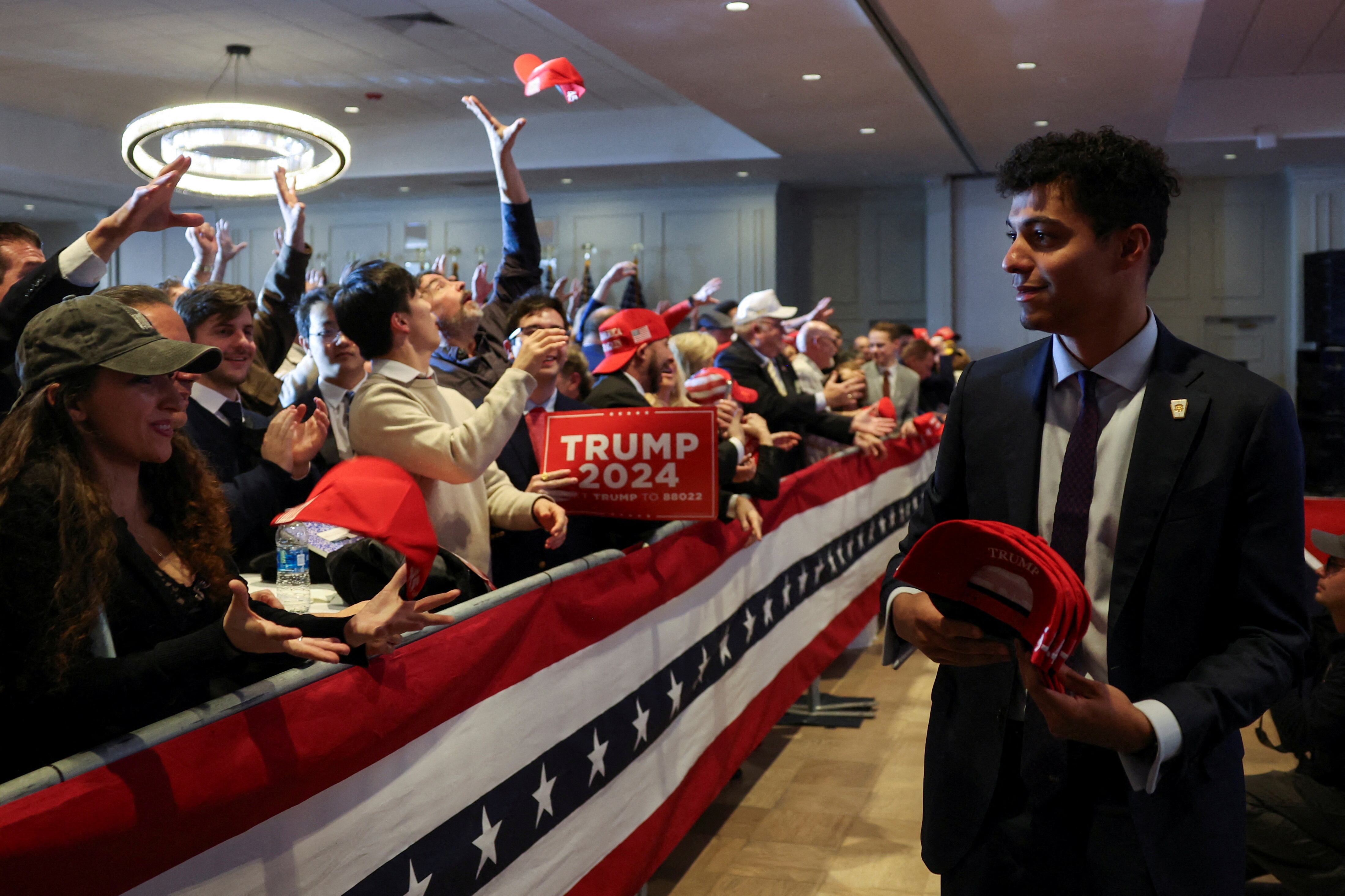 Personal del equipo de Trump reparte gorras entre sus seguidores en Nashua, New Hampshire. 