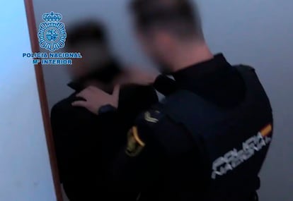 Uno de los detenidos, escoltado por un policía, en la operación por estafar miles de euros a cientos de personas por internet, en una imagen de la Policía Nacional.