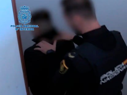 Uno de los detenidos, escoltado por un policía, en la operación por estafar miles de euros a cientos de personas por internet, en una imagen de la Policía Nacional.