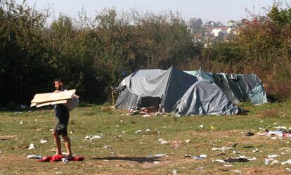 Un hombre transporta cartones en la explanada a las afueras de Velika Kladusa ocupada por tiendas de campaña de cientos de migrantes y refugiados.