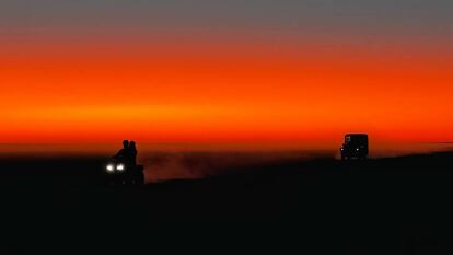 Un todoterreno y un quad avanzan por el salar al atardecer.