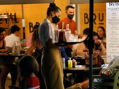 Una camarera sirve una bebida a un cliente en una terraza de Blanes (Girona).