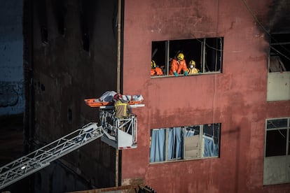 Bomberos rescatando el cuerpo de uno de los primeros fallecidos encontrados el día después del incendio en Gorg.