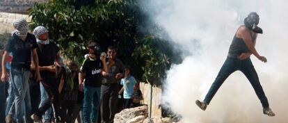 Un palestino devuelve un bote de humo lanzado por el Ej&eacute;rcito en una protesta contra la ocupaci&oacute;n de terrenos cerca de Nablus, en Cisjordania.