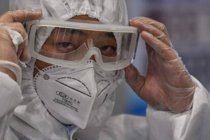 Un agente de seguridad con mascarilla, gafas y traje de protección en el aeropuerto de Shanghái.