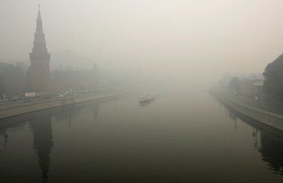 Un ferry navega por el río Moskva, con el Kremlin de fondo cubierto por la niebla.
