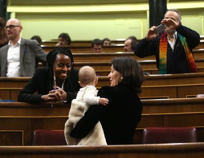 La primera diputada negra en España, Rita Bosaho, sonríe al bebé de Carolina Bescansa durante la sesión constitutiva del Congreso de los Diputados.