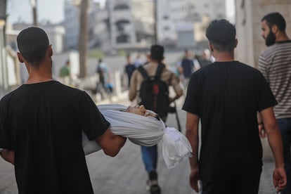 A man carries the body of a child on Monday after the Israeli bombing of a school in Gaza.
