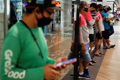 Repartidores de comida esperan pedidos en un centro comercial de Singapur.