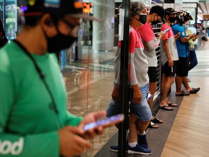 Repartidores de comida esperan pedidos en un centro comercial de Singapur.