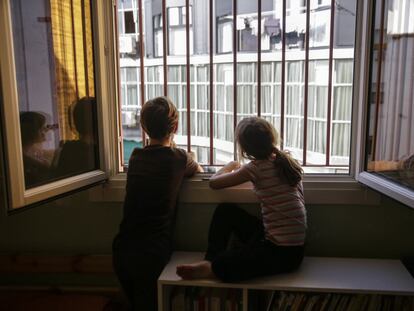 Dos niños miran por la ventana de su dormitorio durante el confinamiento, en Madrid.