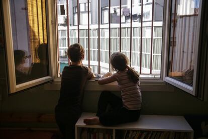 Dos niños miran por la ventana de su dormitorio durante el confinamiento, en Madrid.