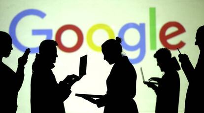 Varias personas utilizan dispositivos móviles ante el logotipo de Google. 