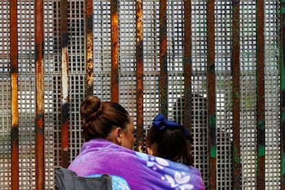 Una mujer, en Tijuana (México), habla con su marido al otro lado de la frontera, en Estados Unidos, el pasado sábado