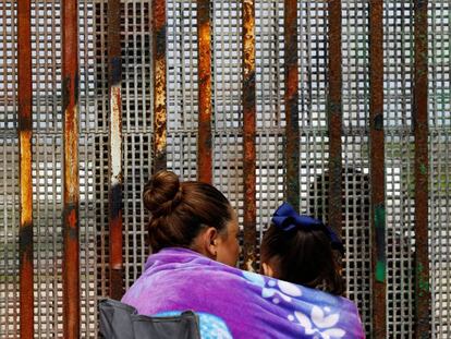 Una mujer, en Tijuana (México), habla con su marido al otro lado de la frontera, en Estados Unidos, el pasado sábado