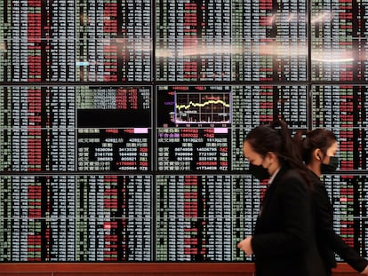 People walk past an electronic stock board at Taipei Exchange in Taipei, Taiwan, Monday, Jan. 30, 2023.