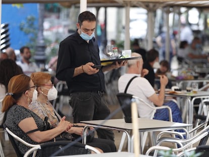 A waiter serves customers at a sidewalk café in L'Hospitalet, Barcelona.