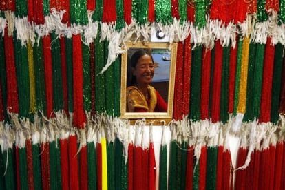 Una mujer sonríe en un espejo mientras compra rosarios en una tienda de Katmandú (Nepal), en el primer día del mes sagrado de Shrawan.
