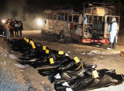 Los cadáveres de los campesinos yacen frente al autobús completamente calcinado.