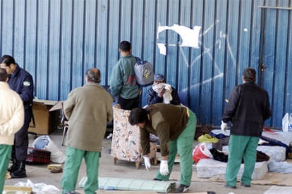 Inmigrantes acampados a las puertas del albergue de temporeros de Jaén recogen sus pertenencias tras la intervención policial de ayer.