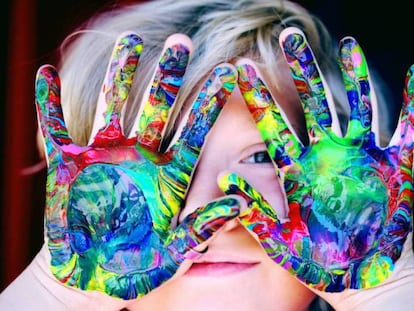 Un niño muestra sus manos pintadas. 
