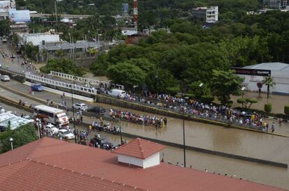 La gente se para al lado de una carretera inundada en la ciudad de Acapulco, México.