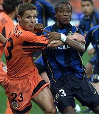El jugador del Valencia Torres se agarra con el interista Kallon.