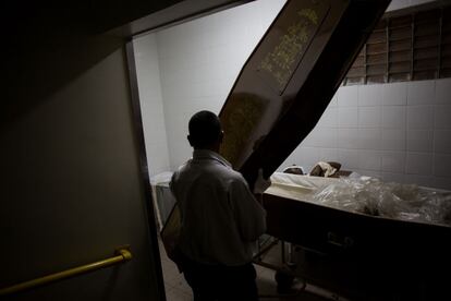 A entrada no necrotério do hospital municipal é permitida pelo segurança do local. O cheiro é forte e causa desconforto. O corpo negro do velho senhor que deve ser enterrado está vestindo apenas uma fralda enquanto seu rosto está coberto por uma extensa tira de esparadrapo. Anos de experiência contribuem para um trabalho preciso na hora de vesti-lo. A família trouxe o terno mais bonito, na cor cinza escuro, camisa azul marinho e uma boina de estimação."Ele adorava este chapeuzinho", suspira a filha mais velha.