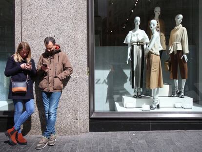 Una pareja consulta en el móvil ante un escaparate, en Madrid.