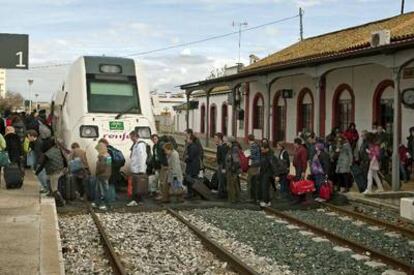 Pasajeros transbordados en autobús desde Antequera cruzan las vías para subir a un tren en la estación de Marchena (Sevilla).