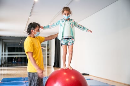 Una niña aprende a mantener el equilibro encima de una bola en la escuela de circo del Price.
