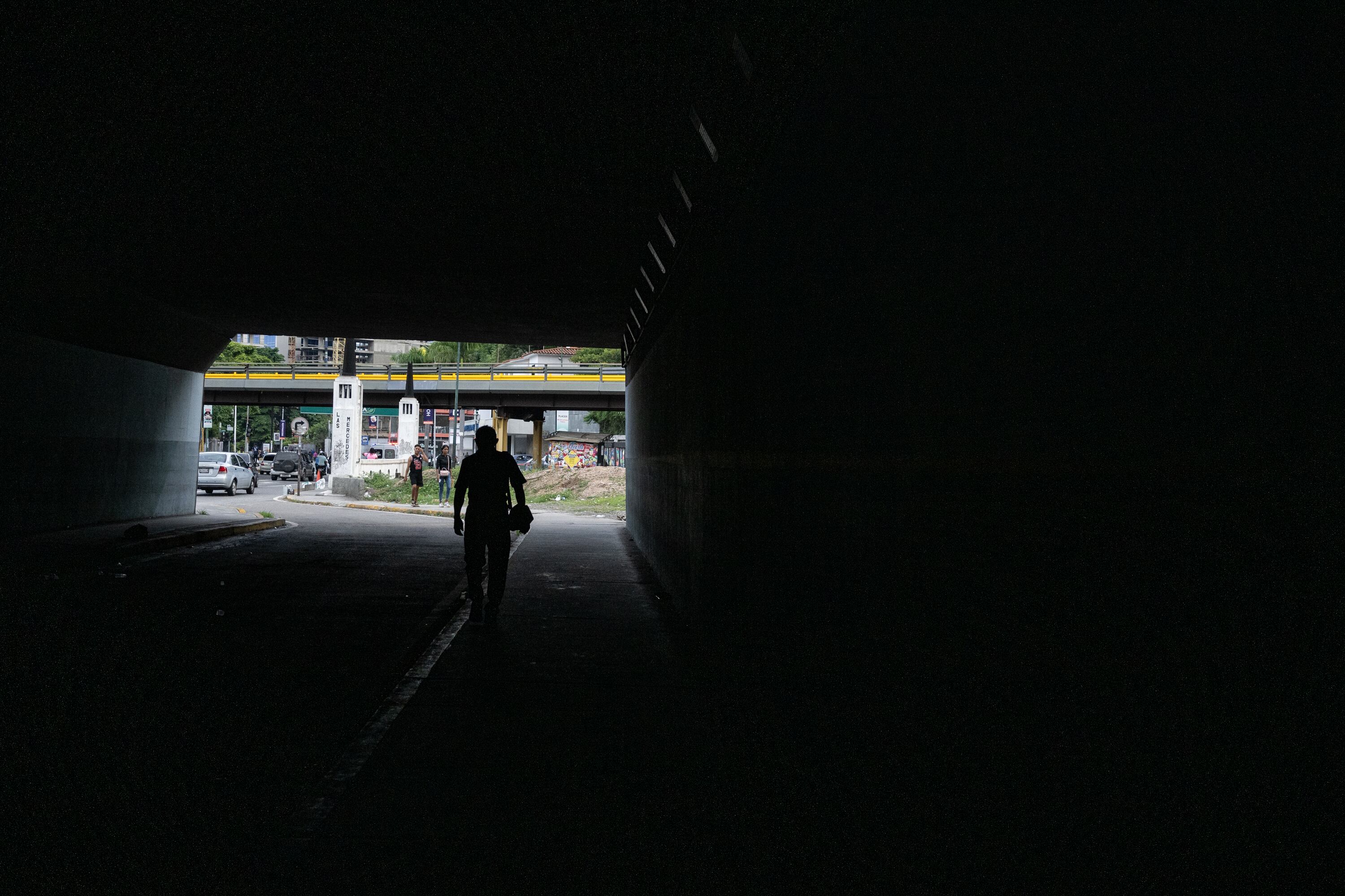 Un hombre recorre un bajopuente en Caracas.